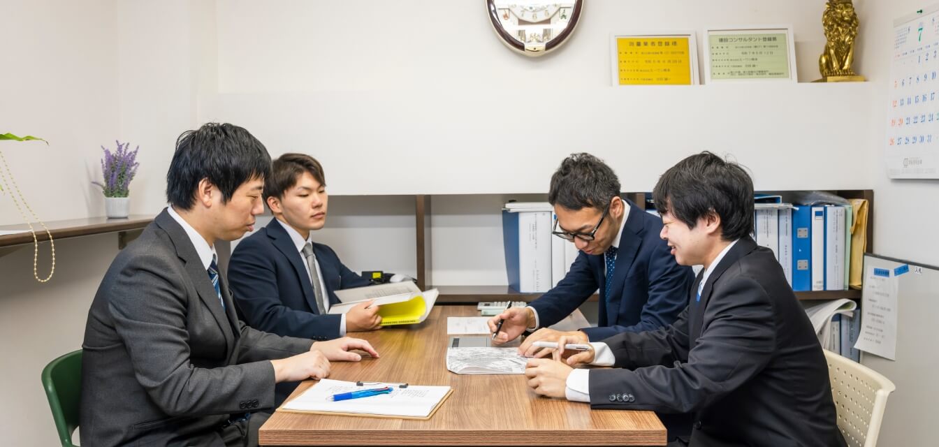 会議室でテーブルを囲んで書類を確認するスタッフ