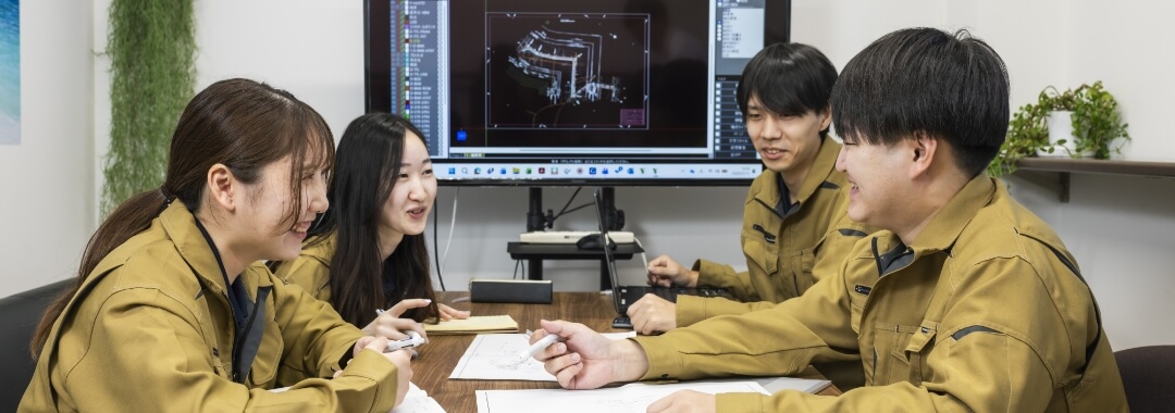 テーブルを囲んで図面を確認しながら打ち合わせするスタッフ