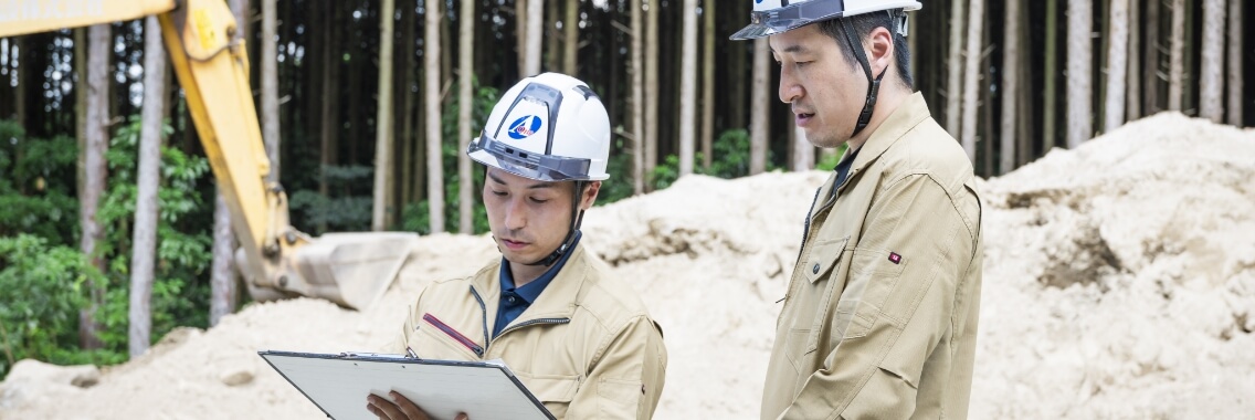 タブレットを手に建設現場で確認作業をする2名の作業員