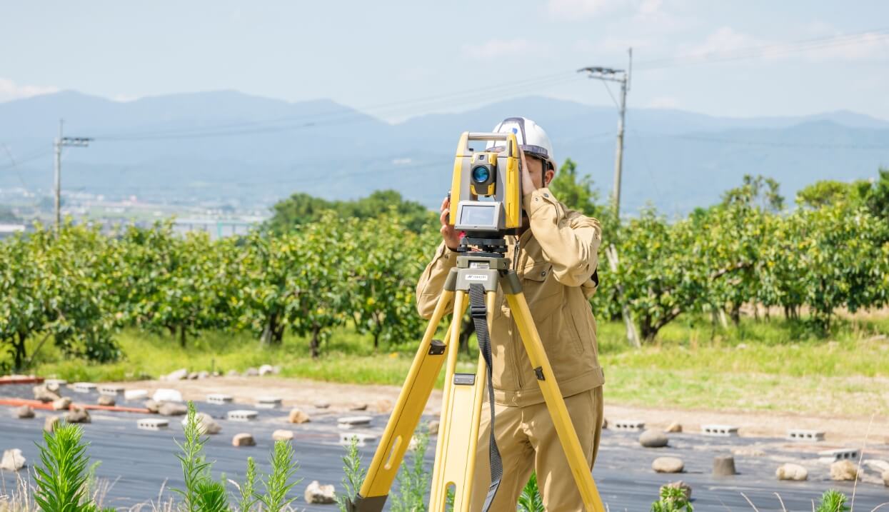 屋外で測量機器を操作する作業員