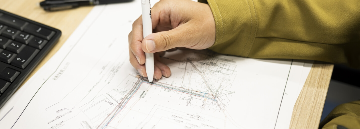 図面にペンを当てて確認する作業員の手元