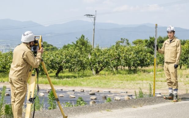 屋外で測量機器を操作する2名の作業員