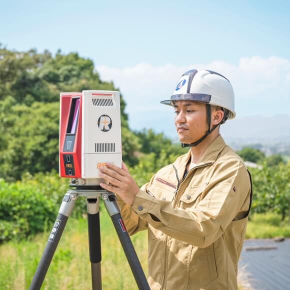 屋外で測量機器を操作する作業員