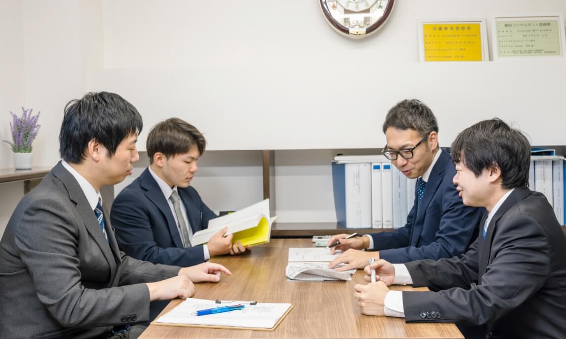テーブルを囲んで打ち合わせをする4名のスタッフ